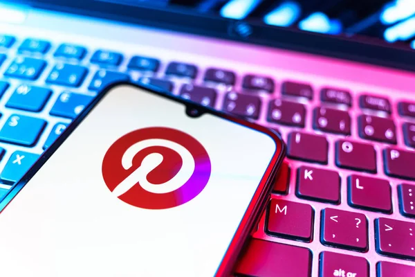 Prag, Çek Cumhuriyeti - 08 19 2025: Pinterest logosunu gösteren klavyenin üzerinde duran cep telefonunun yakından görüntüsü. Pinterest fikirleri görsel olarak keşfetmek ve kaydetmek için bir platformdur..