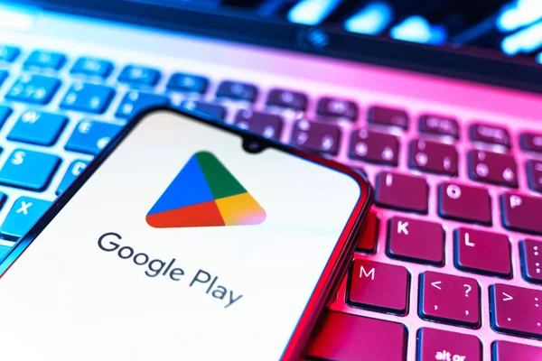 Prag, Çek Cumhuriyeti - 08 19 2025: Google Play logosunu gösteren klavyenin üzerinde duran bir cep telefonunun yakından görüntüsü. Google Play uygulamaları, oyunları ve dijital içeriği indirmek için bir platformdur.