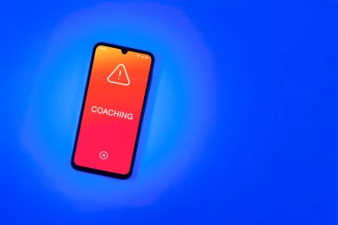 Arka plandaki telefon koçun mesajını gösteriyor. Koçluk, çalışanlara beceri ve performans geliştirme konusunda rehberlik ediyor..