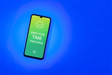 Sade arka plandaki telefon, Çalışan Zaman İzleme metnini gösteriyor. Çalışan Zaman İzleme, çalışanların çalışma saatlerini kaydediyor..