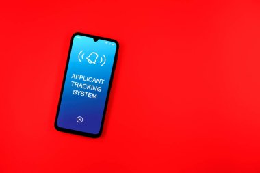 Sade arkaplandaki telefon Uygulamalı İzleme Sistemi metnini gösteriyor. Başvuru İzleme Sistemi işe alım süreçlerini yönetmek için bir yazılımdır.