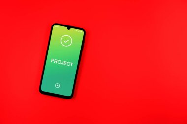 Sade arkaplandaki telefon Proje metnini gösteriyor. Proje, tanımlanmış hedefleri ve son teslim tarihleriyle planlandı.