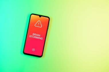 Arka plandaki telefon Beyin Fırtınası metnini gösteriyor. Beyin fırtınası grup tartışması yoluyla fikirler üretmektir..