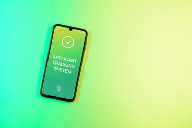 Sade arkaplandaki telefon Uygulamalı İzleme Sistemi metnini gösteriyor. Başvuru İzleme Sistemi işe alım süreçlerini yönetmek için bir yazılımdır.