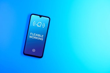 Sade arkaplandaki telefon esnek çalışma metnini gösteriyor. Esnek çalışma saatleri veya iş yerlerini adapte etmektir.