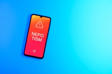 Sade arkaplandaki telefon kayırma metnini gösteriyor. Akraba kayırma, iş yerinde aile veya arkadaşlara kayırmadır..