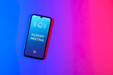 Sade arkaplandaki telefon Başlangıç Toplantısı metnini gösteriyor. Başlangıç Toplantısı bir projeye başlanacak ilk toplantı.