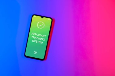 Sade arkaplandaki telefon Uygulamalı İzleme Sistemi metnini gösteriyor. Başvuru İzleme Sistemi işe alım süreçlerini yönetmek için bir yazılımdır.