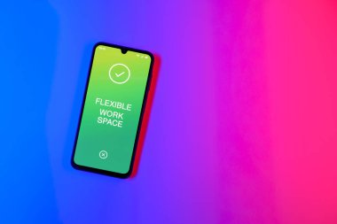 Sade arkaplandaki telefon esnek çalışma alanı metnini gösteriyor. Esnek çalışma alanı, birden fazla kullanım için uyarlanmış bir ofistir..