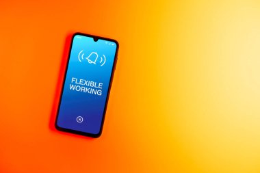 Sade arkaplandaki telefon esnek çalışma metnini gösteriyor. Esnek çalışma saatleri veya iş yerlerini adapte etmektir.