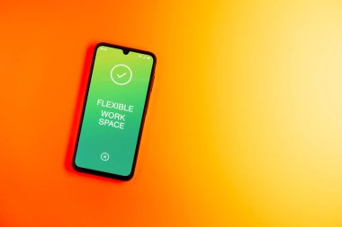 Sade arkaplandaki telefon esnek çalışma alanı metnini gösteriyor. Esnek çalışma alanı, birden fazla kullanım için uyarlanmış bir ofistir..