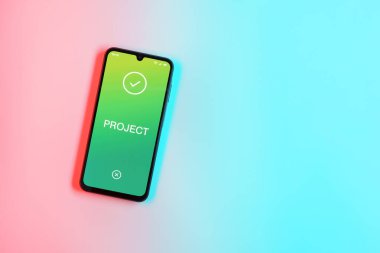 Sade arkaplandaki telefon Proje metnini gösteriyor. Proje, tanımlanmış hedefleri ve son teslim tarihleriyle planlandı.