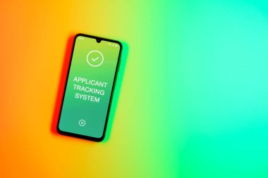 Sade arkaplandaki telefon Uygulamalı İzleme Sistemi metnini gösteriyor. Başvuru İzleme Sistemi işe alım süreçlerini yönetmek için bir yazılımdır.