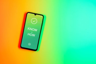 Sade arkaplandaki telefon çokbilmiş metni gösteriyor. Bilgi tecrübeyle kazanılır..