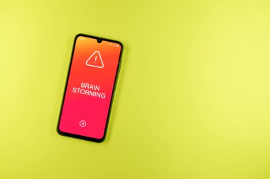 Arka plandaki telefon Beyin Fırtınası metnini gösteriyor. Beyin fırtınası grup tartışması yoluyla fikirler üretmektir..