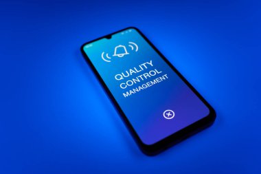 Metin Kalite Kontrol Yönetimi 'ni gösteren bir cep telefonu detayı. Kalite Kontrol Yönetimi ürün veya hizmetlerin standartları karşılamasını sağlıyor.
