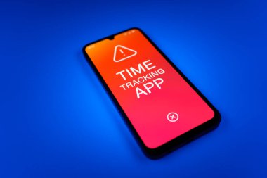 Üniformalı bir arka planda bulunan ve mesaj Zaman İzleme Uygulamasını gösteren bir cep telefonunun ayrıntısı. Zaman İzleme Uygulaması günlük kaydı çalışma saatleri için bir yazılımdır.