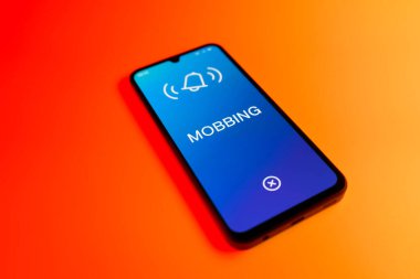 Üniformalı bir arka planda duran cep telefonunun Mobbing metnini gösteren bir detayı. Gangsterlik iş arkadaşları arasında zorbalıktır..