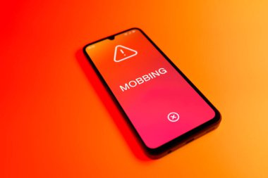Üniformalı bir arka planda duran cep telefonunun Mobbing metnini gösteren bir detayı. Gangsterlik iş arkadaşları arasında zorbalıktır..