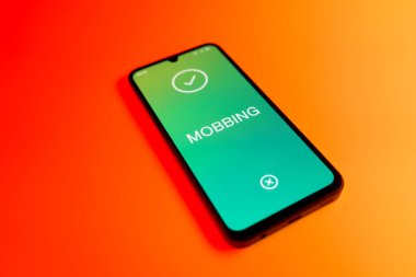 Üniformalı bir arka planda duran cep telefonunun Mobbing metnini gösteren bir detayı. Gangsterlik iş arkadaşları arasında zorbalıktır..