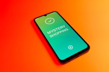 Üniformalı bir arka planda duran ve Mystery 'nin alışveriş mesajlarını gösteren bir cep telefonu detayı. Gizemli alışveriş, test müşterileri aracılığıyla hizmet kalitesini değerlendirmektir..