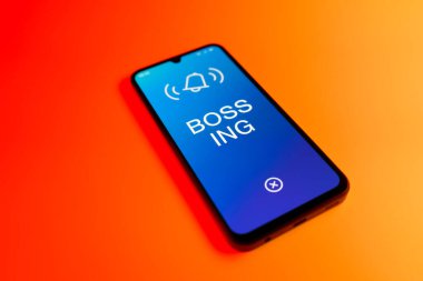 Üniformalı bir arka planda duran cep telefonunun ayrıntıları Bossing 'in mesajlarını gösteriyor. Patronluk, amirin zorbalık ettiği işyeridir..