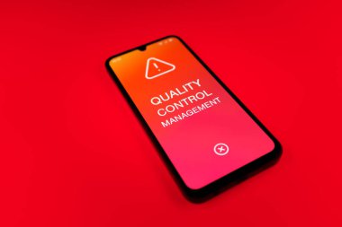 Metin Kalite Kontrol Yönetimi 'ni gösteren bir cep telefonu detayı. Kalite Kontrol Yönetimi ürün veya hizmetlerin standartları karşılamasını sağlıyor.