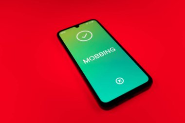 Üniformalı bir arka planda duran cep telefonunun Mobbing metnini gösteren bir detayı. Gangsterlik iş arkadaşları arasında zorbalıktır..