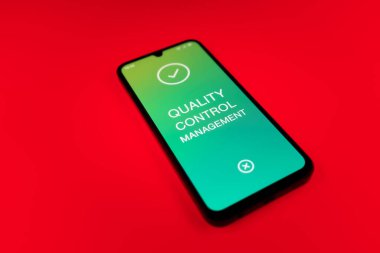 Metin Kalite Kontrol Yönetimi 'ni gösteren bir cep telefonu detayı. Kalite Kontrol Yönetimi ürün veya hizmetlerin standartları karşılamasını sağlıyor.
