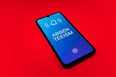 Üniformalı bir arkaplanda yatan cep telefonunun ayrıntıları eksik metni gösteriyor. Geçerli nedenler olmadan devamsızlık sık sık işten yoksunluktur.
