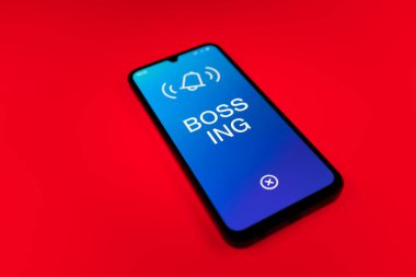 Üniformalı bir arka planda duran cep telefonunun ayrıntıları Bossing 'in mesajlarını gösteriyor. Patronluk, amirin zorbalık ettiği işyeridir..