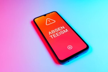 Üniformalı bir arkaplanda yatan cep telefonunun ayrıntıları eksik metni gösteriyor. Geçerli nedenler olmadan devamsızlık sık sık işten yoksunluktur.