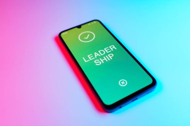 Üniformalı bir arkaplanda yatan cep telefonunun bir ayrıntısı metin liderliğini gösteriyor. Liderlik bir takıma rehberlik etme ve onlara ilham verme yeteneğidir..