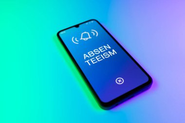 Üniformalı bir arkaplanda yatan cep telefonunun ayrıntıları eksik metni gösteriyor. Geçerli nedenler olmadan devamsızlık sık sık işten yoksunluktur.