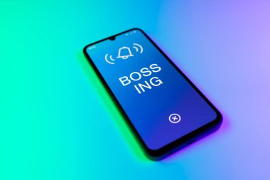 Üniformalı bir arka planda duran cep telefonunun ayrıntıları Bossing 'in mesajlarını gösteriyor. Patronluk, amirin zorbalık ettiği işyeridir..