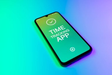 Üniformalı bir arka planda bulunan ve mesaj Zaman İzleme Uygulamasını gösteren bir cep telefonunun ayrıntısı. Zaman İzleme Uygulaması günlük kaydı çalışma saatleri için bir yazılımdır.