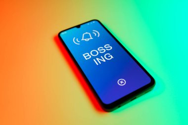 Üniformalı bir arka planda duran cep telefonunun ayrıntıları Bossing 'in mesajlarını gösteriyor. Patronluk, amirin zorbalık ettiği işyeridir..