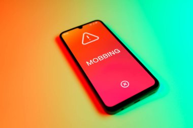 Üniformalı bir arka planda duran cep telefonunun Mobbing metnini gösteren bir detayı. Gangsterlik iş arkadaşları arasında zorbalıktır..
