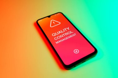 Metin Kalite Kontrol Yönetimi 'ni gösteren bir cep telefonu detayı. Kalite Kontrol Yönetimi ürün veya hizmetlerin standartları karşılamasını sağlıyor.