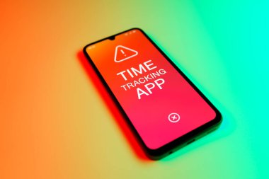 Üniformalı bir arka planda bulunan ve mesaj Zaman İzleme Uygulamasını gösteren bir cep telefonunun ayrıntısı. Zaman İzleme Uygulaması günlük kaydı çalışma saatleri için bir yazılımdır.