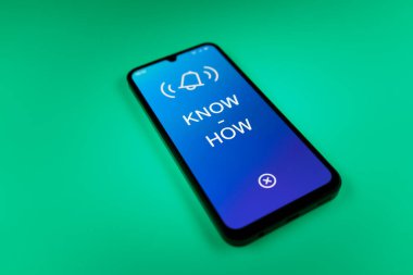 Üniformalı bir arka planda duran cep telefonunun metni ile ilgili bir detay. Bilgi tecrübeyle kazanılır..
