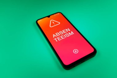 Üniformalı bir arkaplanda yatan cep telefonunun ayrıntıları eksik metni gösteriyor. Geçerli nedenler olmadan devamsızlık sık sık işten yoksunluktur.