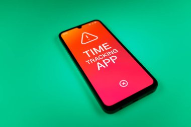 Üniformalı bir arka planda bulunan ve mesaj Zaman İzleme Uygulamasını gösteren bir cep telefonunun ayrıntısı. Zaman İzleme Uygulaması günlük kaydı çalışma saatleri için bir yazılımdır.