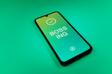 Üniformalı bir arka planda duran cep telefonunun ayrıntıları Bossing 'in mesajlarını gösteriyor. Patronluk, amirin zorbalık ettiği işyeridir..