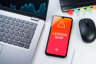 Ofis masası dizüstü bilgisayarlı ve telefonlu Liderlik metnini gösteriyor. Liderlik bir takıma rehberlik etme ve onlara ilham verme yeteneğidir..