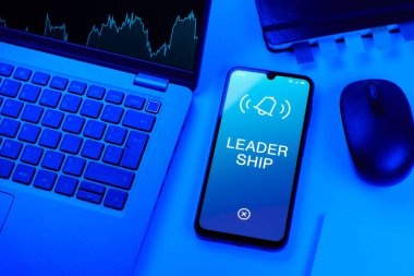 Ofis masası dizüstü bilgisayarlı ve telefonlu Liderlik metnini gösteriyor. Liderlik bir takıma rehberlik etme ve onlara ilham verme yeteneğidir..