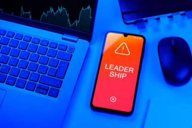 Ofis masası dizüstü bilgisayarlı ve telefonlu Liderlik metnini gösteriyor. Liderlik bir takıma rehberlik etme ve onlara ilham verme yeteneğidir..