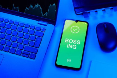 Ofis masası dizüstü bilgisayarı ve telefonu Bossing 'in mesajını gösteriyor. Patronluk, amirin zorbalık ettiği işyeridir..
