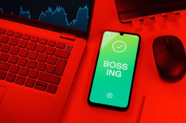 Ofis masası dizüstü bilgisayarı ve telefonu Bossing 'in mesajını gösteriyor. Patronluk, amirin zorbalık ettiği işyeridir..