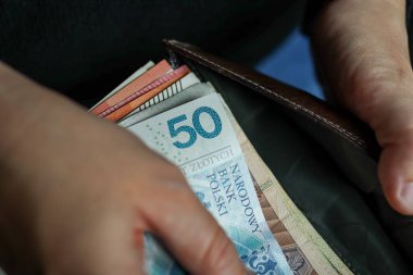 Cüzdanda 50 PLN banknot ve diğer para birimlerini gösteren Polonya banknotlarını tutan ellerin kapatılması